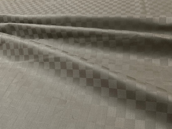 Close-up view of a beige checkered pattern bed sheet fabric .