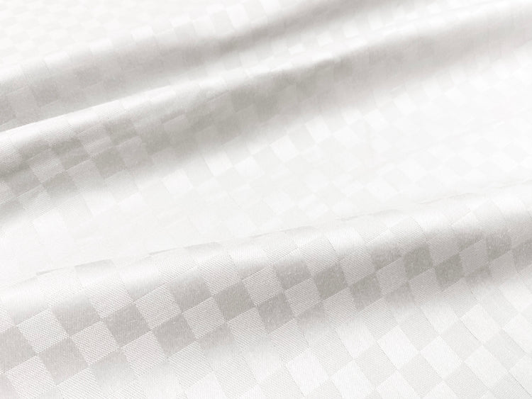 Close-up view of a white custom bed sheet with a sateen self square weave pattern 2.