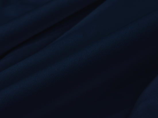Dark blue fabric draped in soft, flowing folds, creating a sense of depth and texture. 