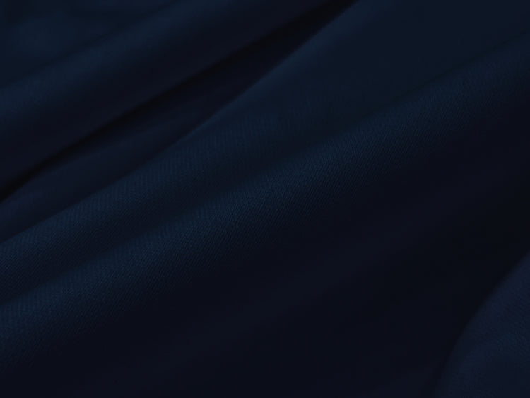 Dark blue fabric draped in soft, flowing folds, creating a sense of depth and texture. 