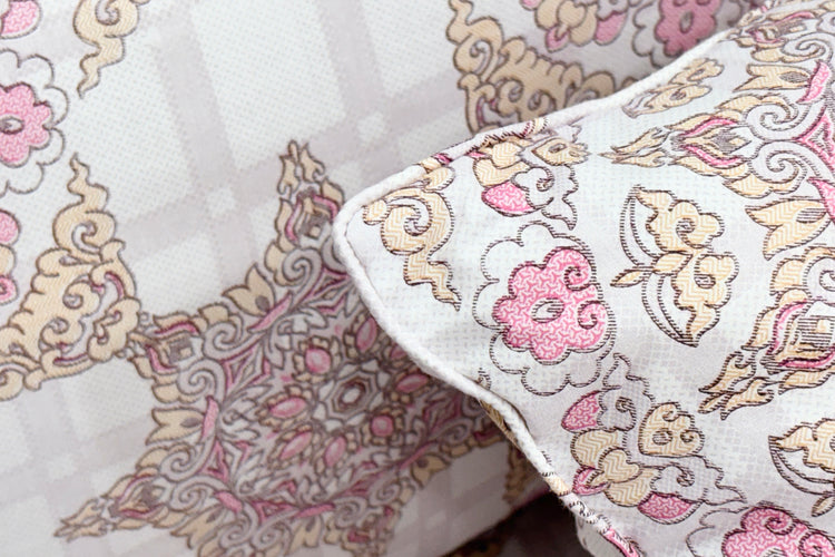 Ornate pillow with intricate floral patterns in pink, beige, and white tones