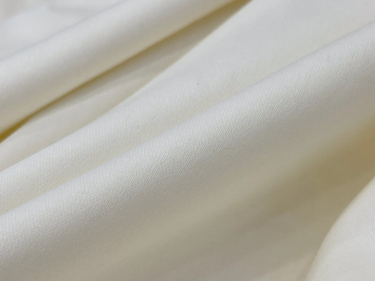 Smooth, cream-colored fabric with soft folds creating a gentle wave pattern. 