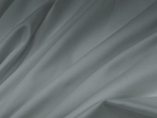 Smooth grey fabric bedsheet with soft, flowing folds creating gentle shadows and highlights.