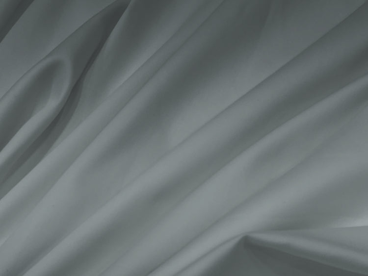 Smooth grey fabric bedsheet with soft, flowing folds creating gentle shadows and highlights.