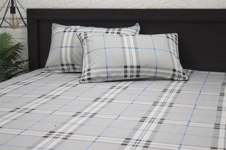 Two square pillows with a geometric pattern on a bed, primarily in gray, blue, and white colors 1.