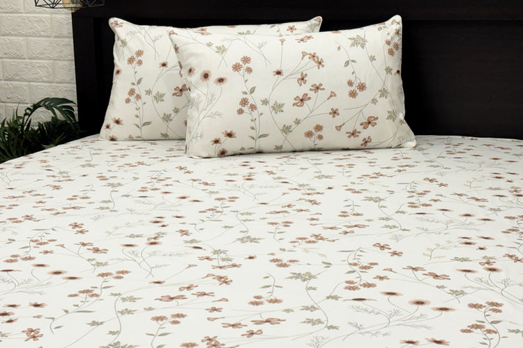 White cotton bedsheet with brown floral  print and two pillows .