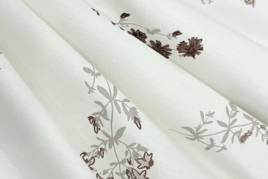 White fabric bedsheet with light gray and dark brown floral pattern.