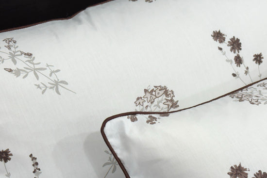 White pillowcases featuring delicate brown floral embroidery and dark trim 