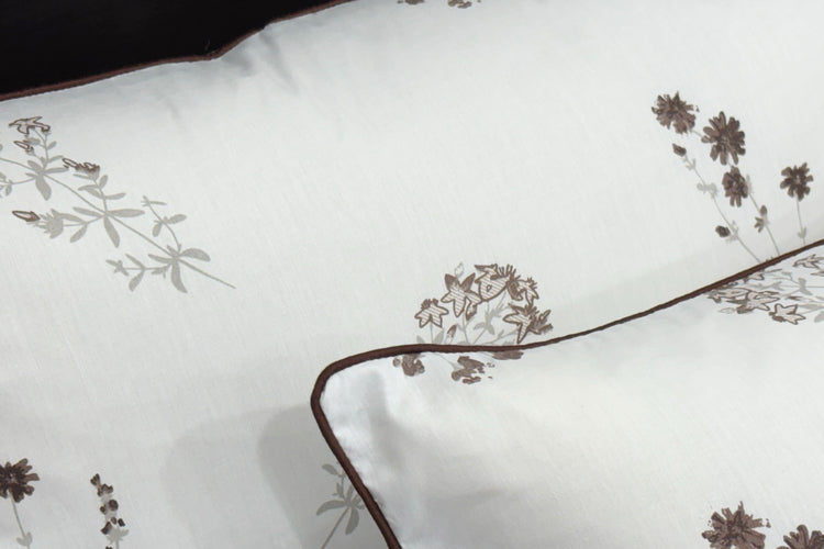 White pillowcases featuring delicate brown floral embroidery and dark trim 