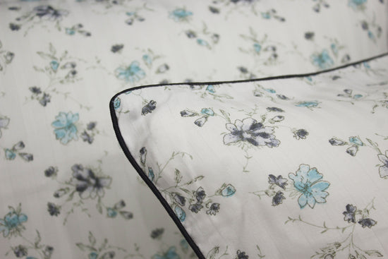 bedsheet and  pillow with a floral print design, shades of blue and green .
