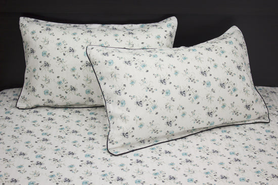 bedsheet and two pillows with a floral print design, shades of blue and green .