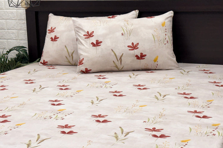 cotton white bedsheet with floral and leaf print and two pillows neatly arranged on bed
