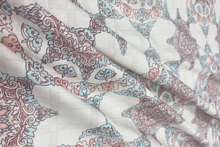 geometric patterns bedsheet in shades of white, blue, and pink with gently folded.