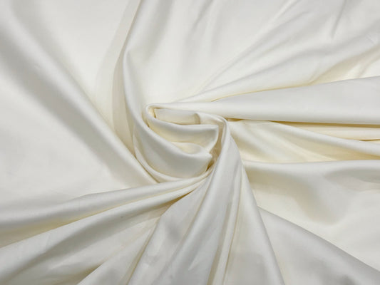 Smooth white silk fabric gracefully draped, forming a gentle spiral at the center. 