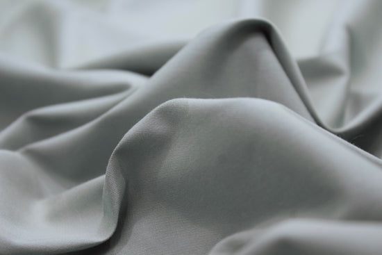 smooth, gray fabric with gentle folds creating a wave-like texture. 