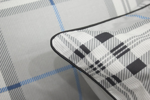 square pillow with a geometric pattern  bedsheet on a bed, primarily in gray, blue, and white colors.