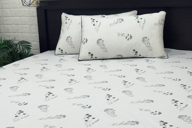 white bed sheets featuring a floral pattern. Two matching pillows .