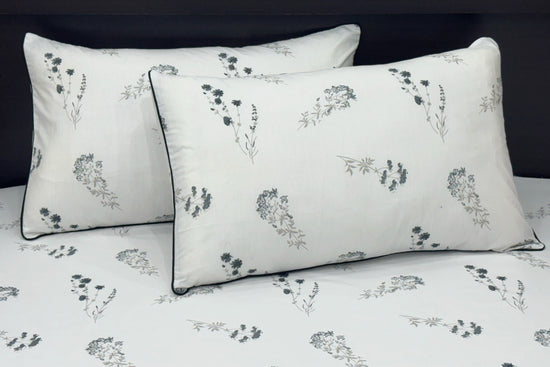 white bed sheets featuring a floral pattern. Two matching pillows 1.