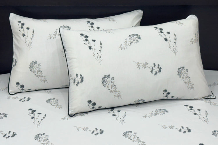white bed sheets featuring a floral pattern. Two matching pillows 1.