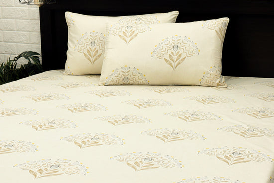 white cotton bedsheet with brown,blue floral printed and matching pillows neaty arranged on bed