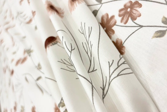 white cotton bedsheet with brown floral print arranged on bed