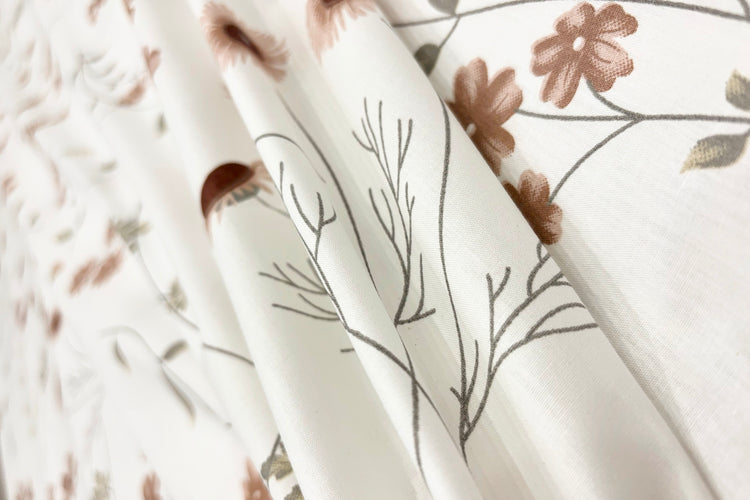 white cotton bedsheet with brown floral print arranged on bed