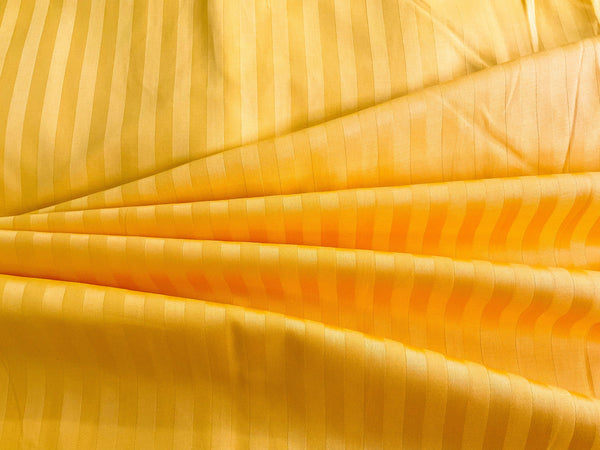A close-up image of a golden yellow striped sateen bed sheet.