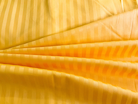 A close-up image of a golden yellow striped sateen bed sheet.