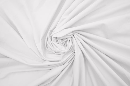 A close-up image of a white, percale weave bed sheet with a focus on texture .