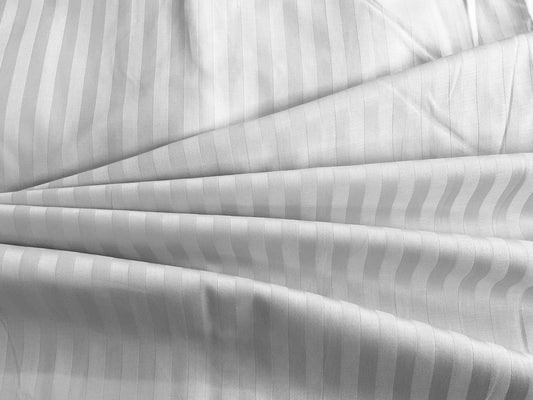 A close-up of a white sateen bed sheet with self stripes weave pattern.