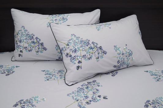 A set of two pillows with a floral print design bedsheet in shades of purple 