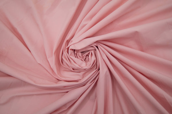 A swirled bed sheet in a solid pink color 