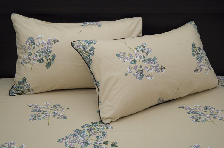 Two beige pillows with floral patterns, featuring small purple and green flowers.