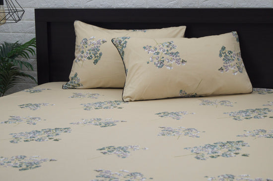 Two beige pillows with floral patterns, featuring small purple and green flowers 1.
